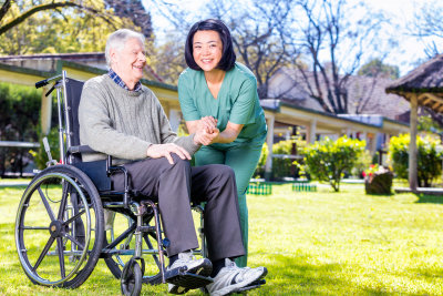 asian nurse happy with caucasian elder patient on wheelchair